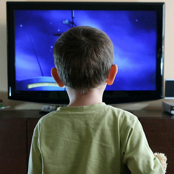 young boy, viewed from behind, fixated on tv screen