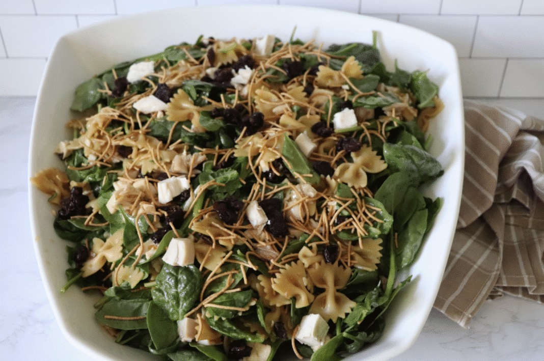 teriyaki chicken and bowtie pasta salad in a large white serving bowl with a striped linen in the background.