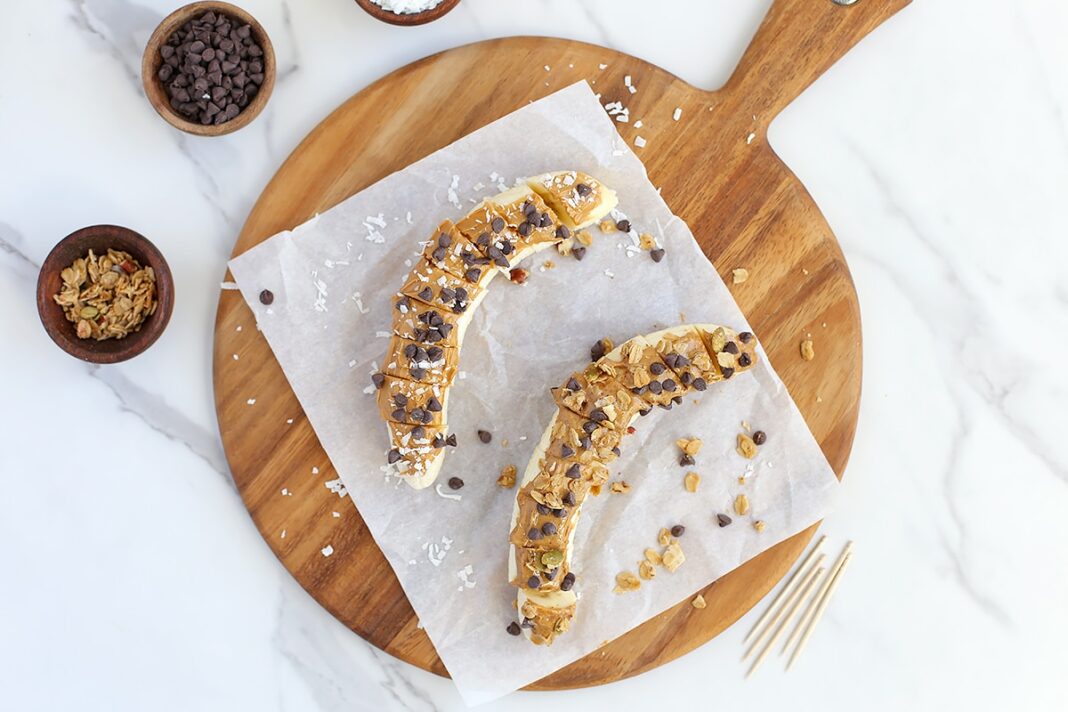 banana sushi snack with mini chocolate chips and shredded coconut on a wooden cutting board