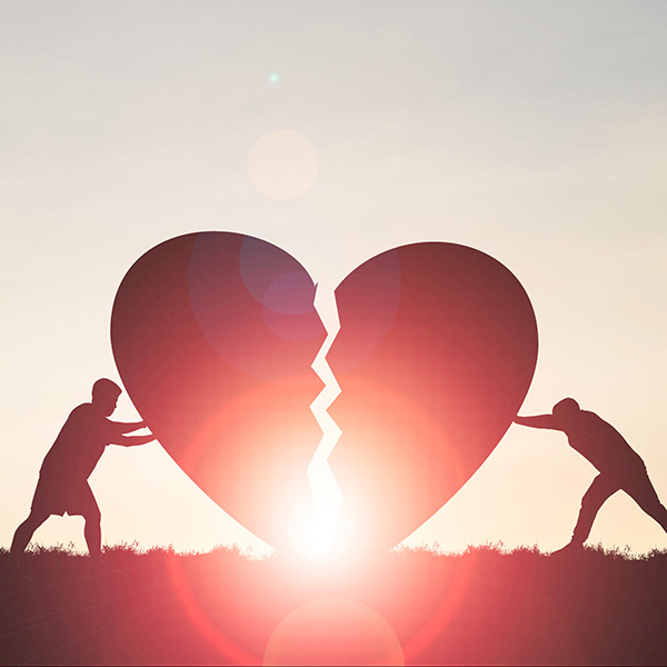 Two people pushing a large heart together, that is cracked down the middle, symbolizing deal with grief