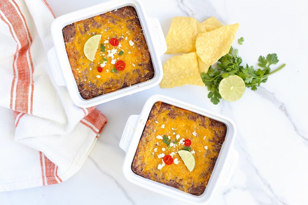 black bean dip in small serving dishes with a striped linen and tortilla chips in the background