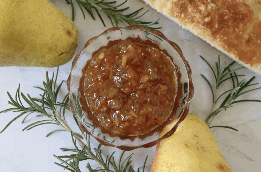 homemade pear preserves with rosemary and honey in a glass dish with fresh pears and a crusty bread