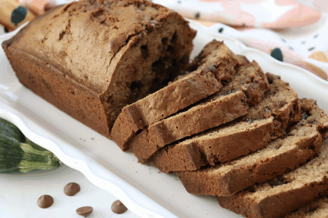 chocolate chip zucchini bread sliced on a white serving platter with a floral linen in the background