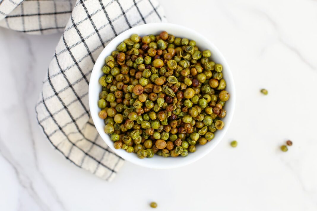 crunchy oven roasted peas in a serving bowl with a checkered towel.