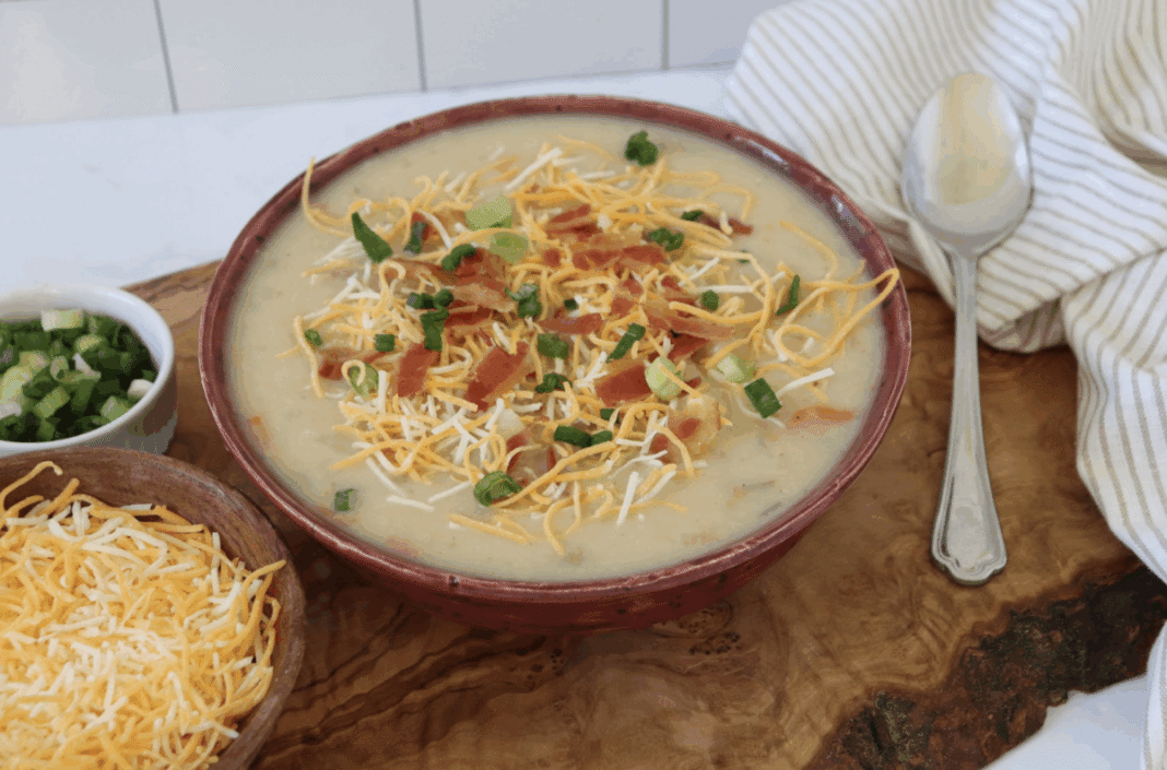 crockpot potato and bacon soup in a serving bowl with cheese and green onions